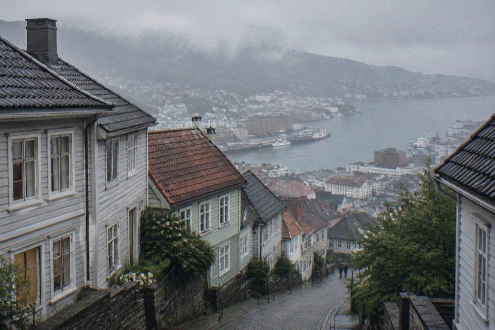 Timber houses on a steep hillside street in Bergen with a faded painted mural on an end wall.