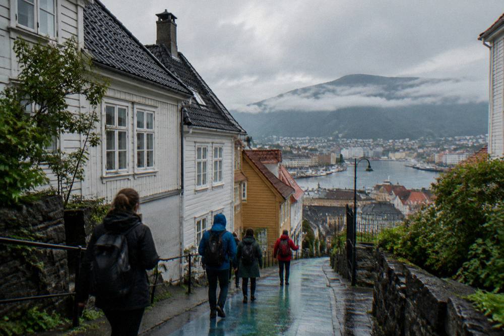 A small group of visitors following a guide down a painted lane in central Bergen.