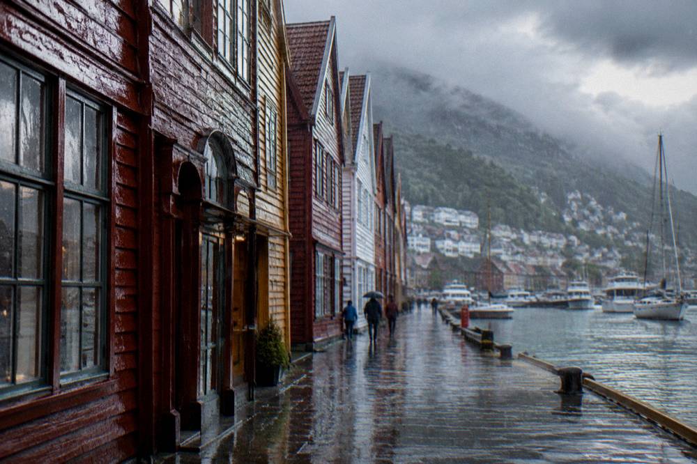 Heavy rain falling on the historic wooden buildings of the Hanseatic wharf with reflections on wet stone