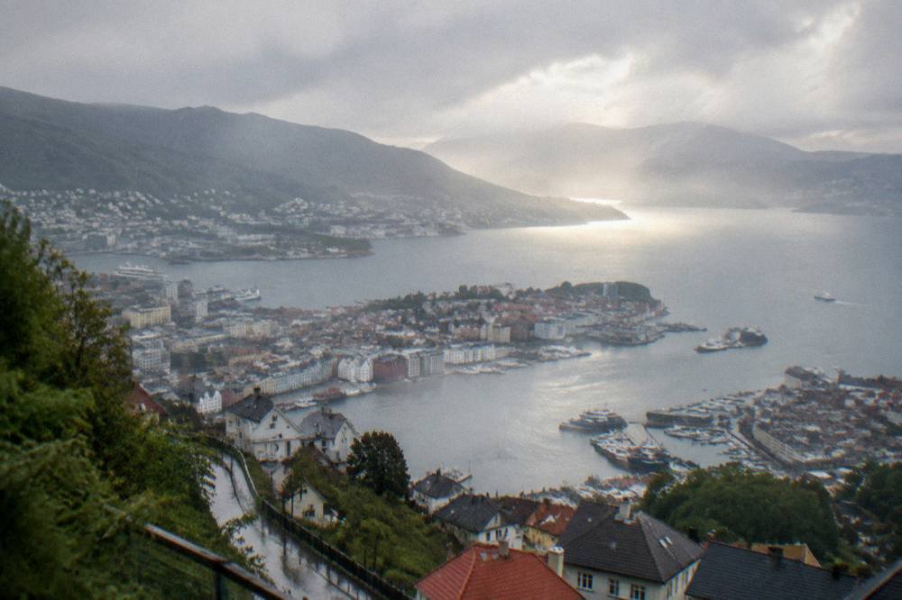 A break in the clouds casting light across the harbour and mountain ridges around Bergen after rain
