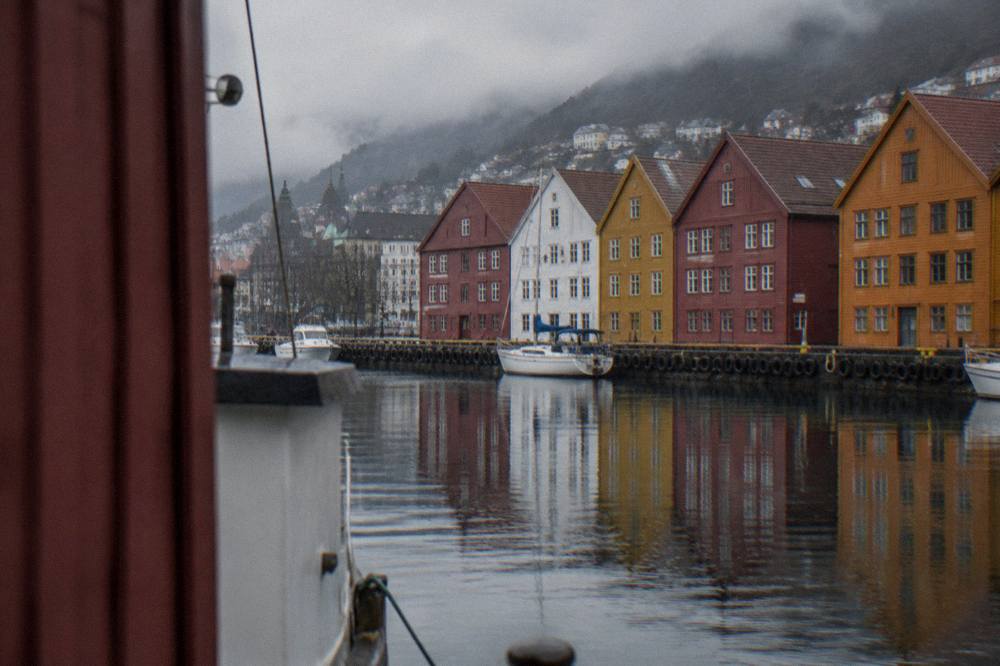 Closer view of the historic wharf in Bergen with tall coloured wooden warehouses reflected in still harbour water