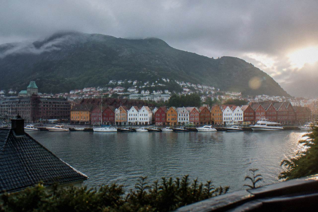 Colourful historic wooden buildings along the waterfront of Bergen with a mountain rising behind the town