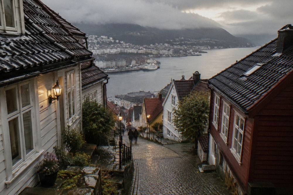 Narrow cobblestone street of old wooden houses on a hillside above the Bergen harbour