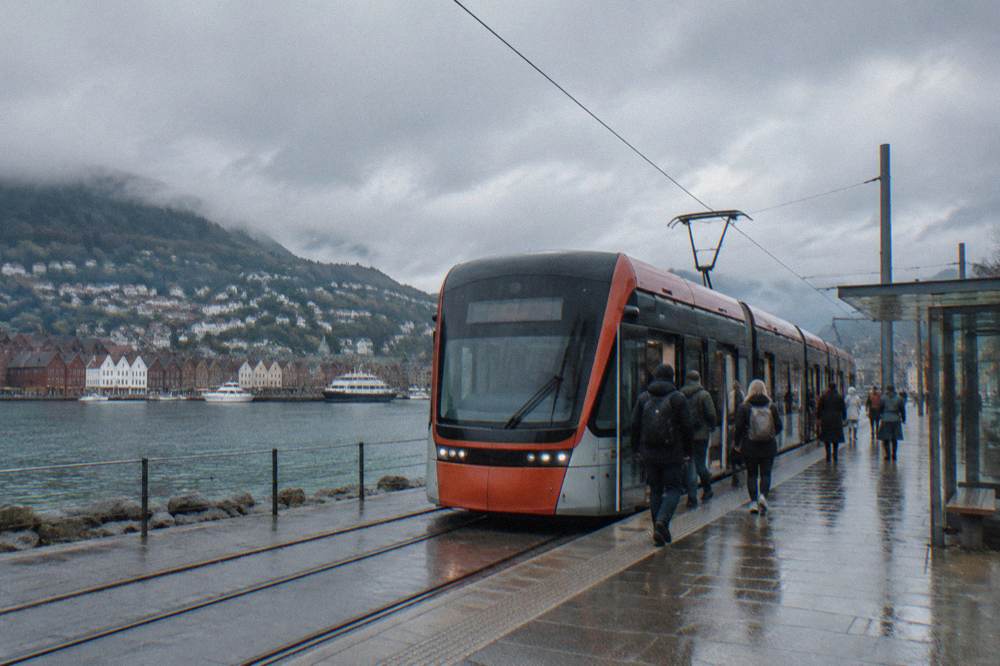 Passengers boarding a modern light rail tram at a Bergen city stop