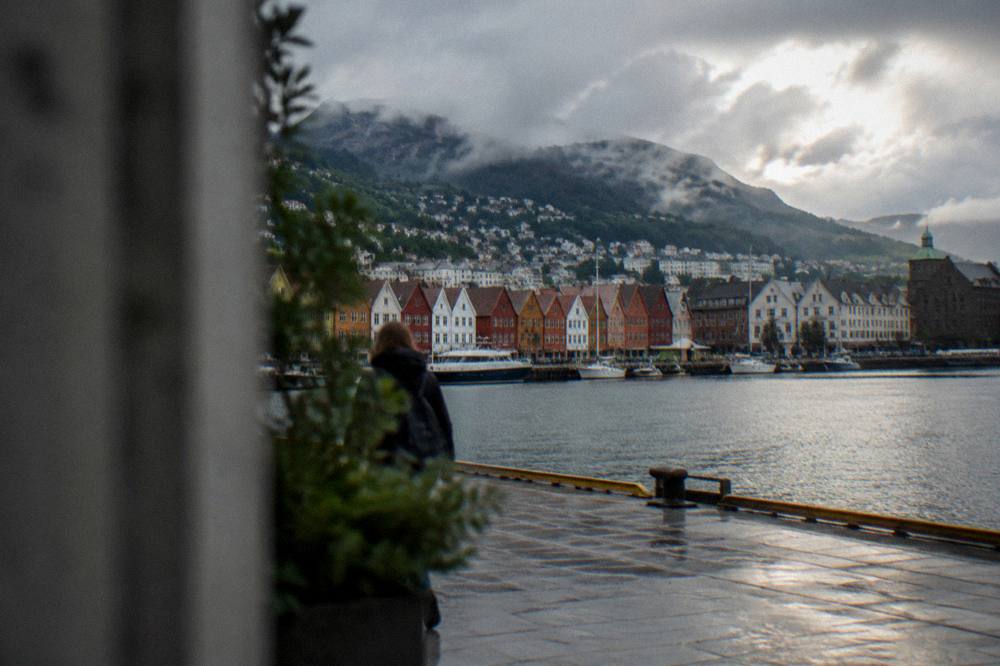 Rain clouds and breaking sunshine over the mountains surrounding a Norwegian coastal city