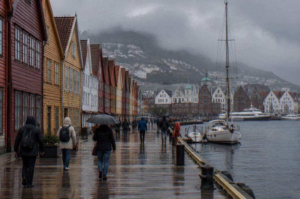 Visitors walking between the colourful wooden buildings of a historic wharf in Bergen