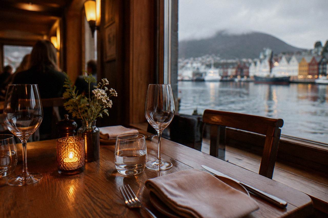 Tables set for dinner inside a warm Bergen restaurant with wooden interiors