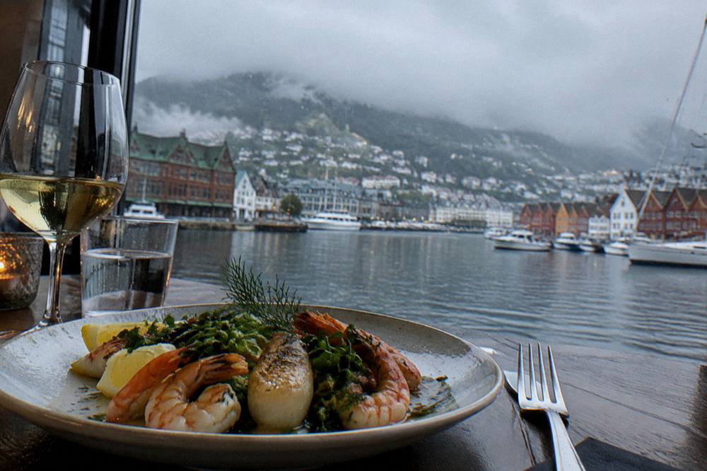 Fork and plate of seafood at a set restaurant table by a window in Bergen