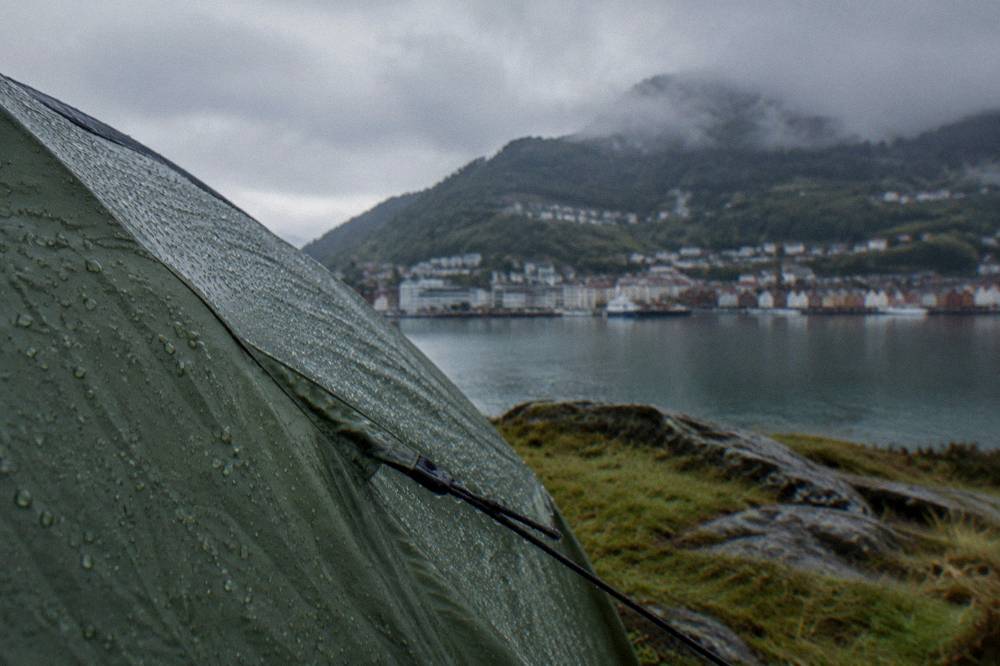 Water droplets on a tent fly in grey morning weather with green hills behind