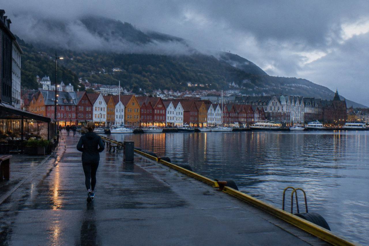 Colourful wooden houses along the waterfront in Bergen with a mountain rising behind the city