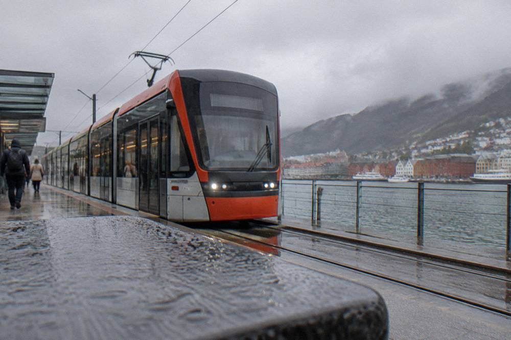 A light rail tram stopping at an outdoor station in Bergen on a grey day