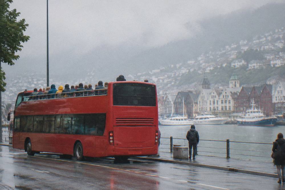 An open-top sightseeing bus parked on a street in central Bergen