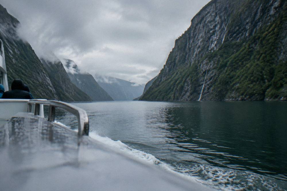 A tour boat cruising a narrow fjord with steep cliffs on both sides near Bergen