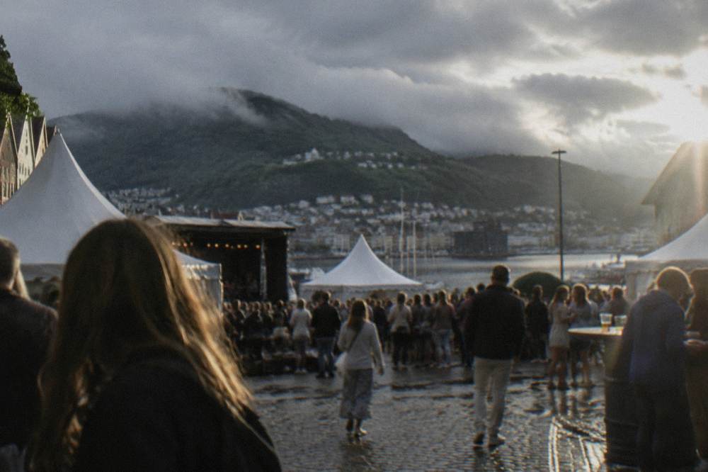 Festival crowds and white tents in a Bergen square on a summer evening