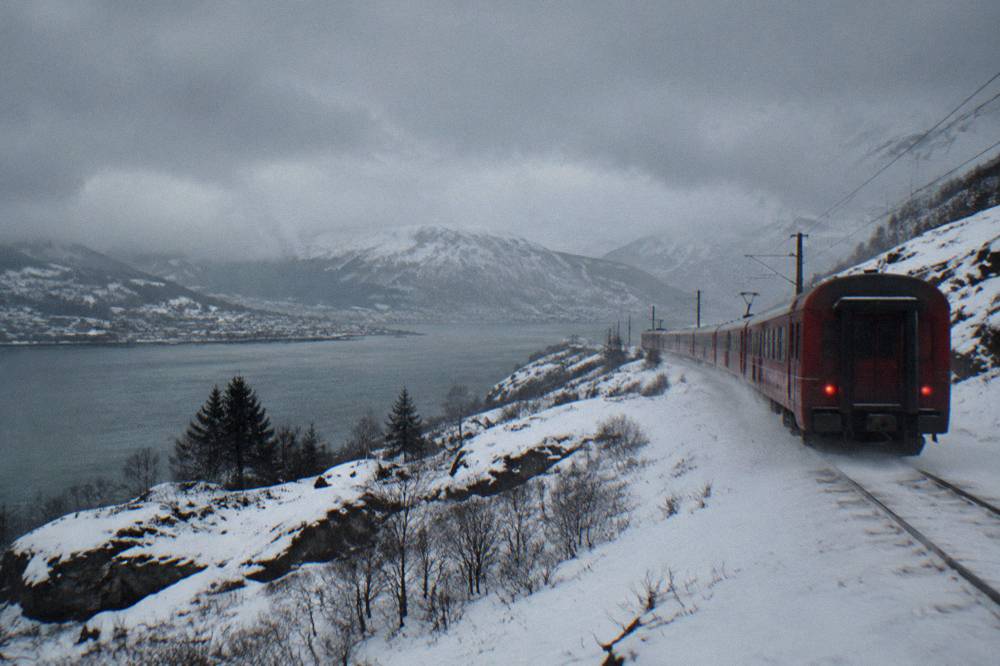 A red train crossing a snow-covered mountain plateau in Norway