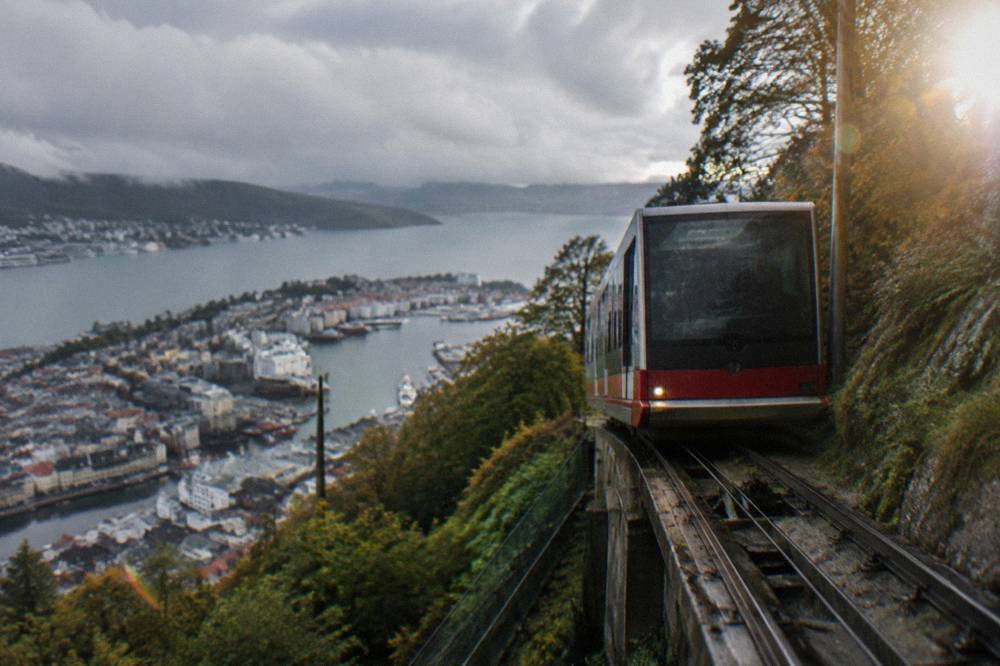 A funicular car climbing the forested slope above the rooftops of Bergen