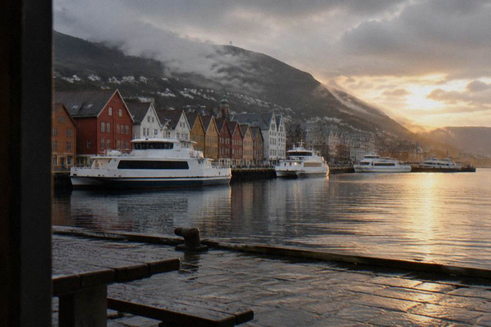 White ferries moored along the waterfront of Bergen harbour near the old wharf buildings