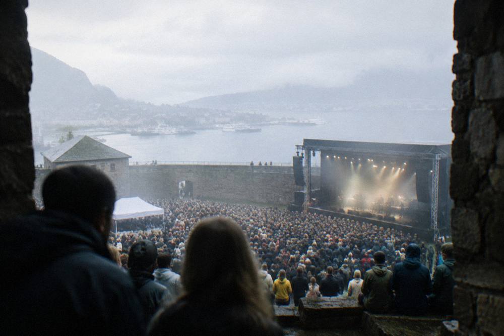 Festival crowds gathered at an outdoor concert inside the stone walls of a fortress in Bergen