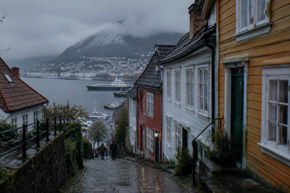 A narrow street of colourful wooden townhouses on a hillside above the Bergen harbour