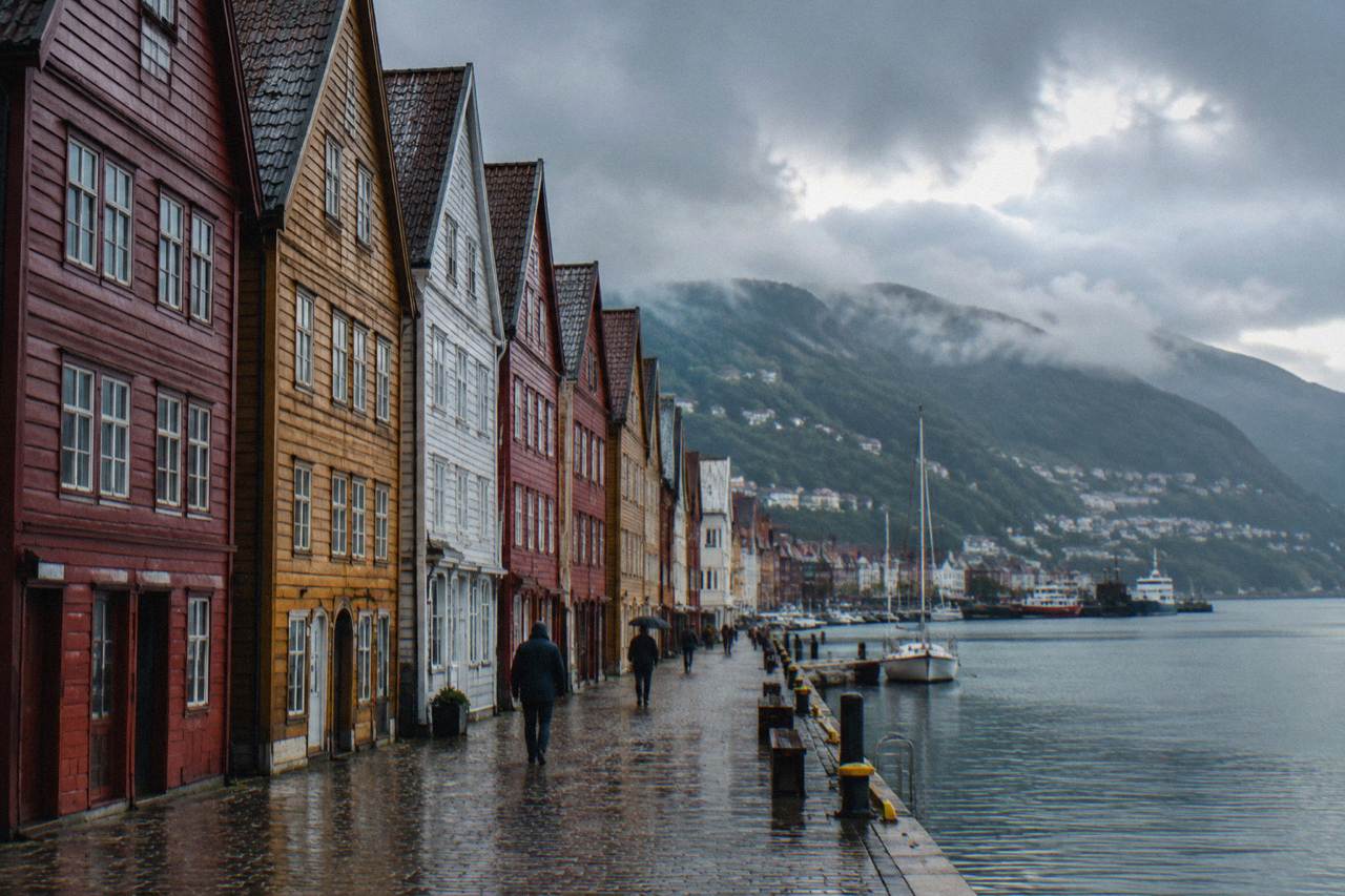 Rain-slicked wooden buildings along Bryggen wharf in Bergen with a calm harbour in the background