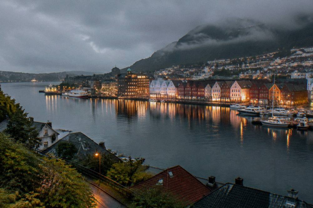 Bergen's harbour and illuminated buildings reflected in still water on a dark evening