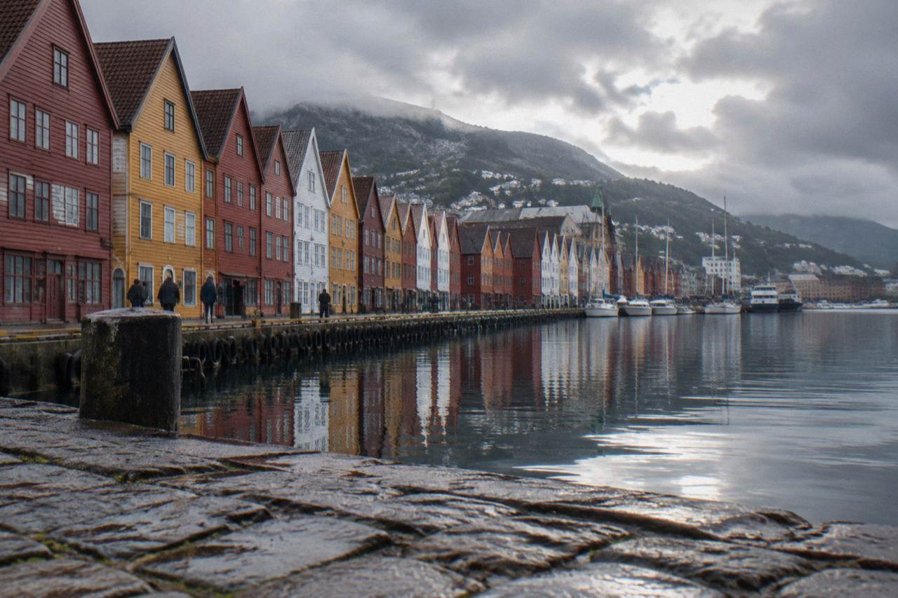 Colorful wooden buildings along the Bryggen wharf in Bergen reflected in the harbour water on an overcast day