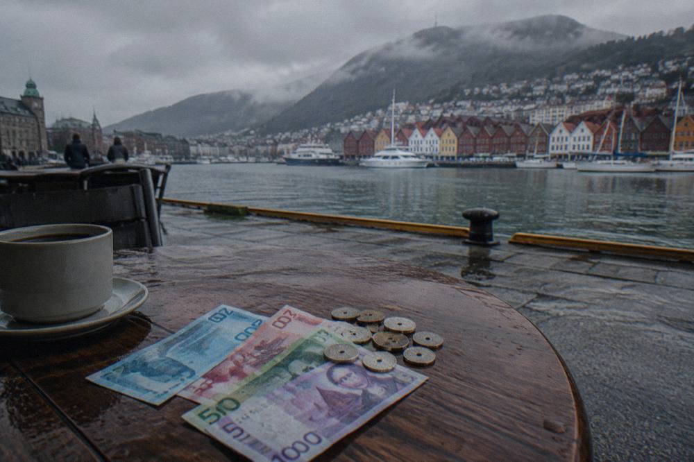 Norwegian krone banknotes and coins laid out on a wooden cafe table beside a receipt
