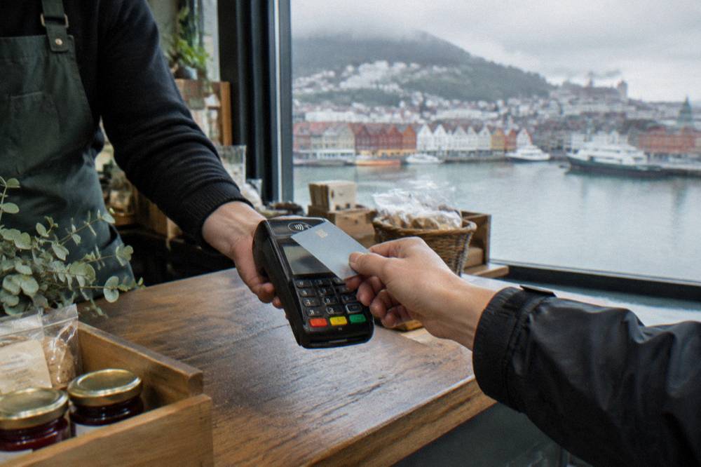 A contactless card payment being made at a small shop counter in a Nordic city