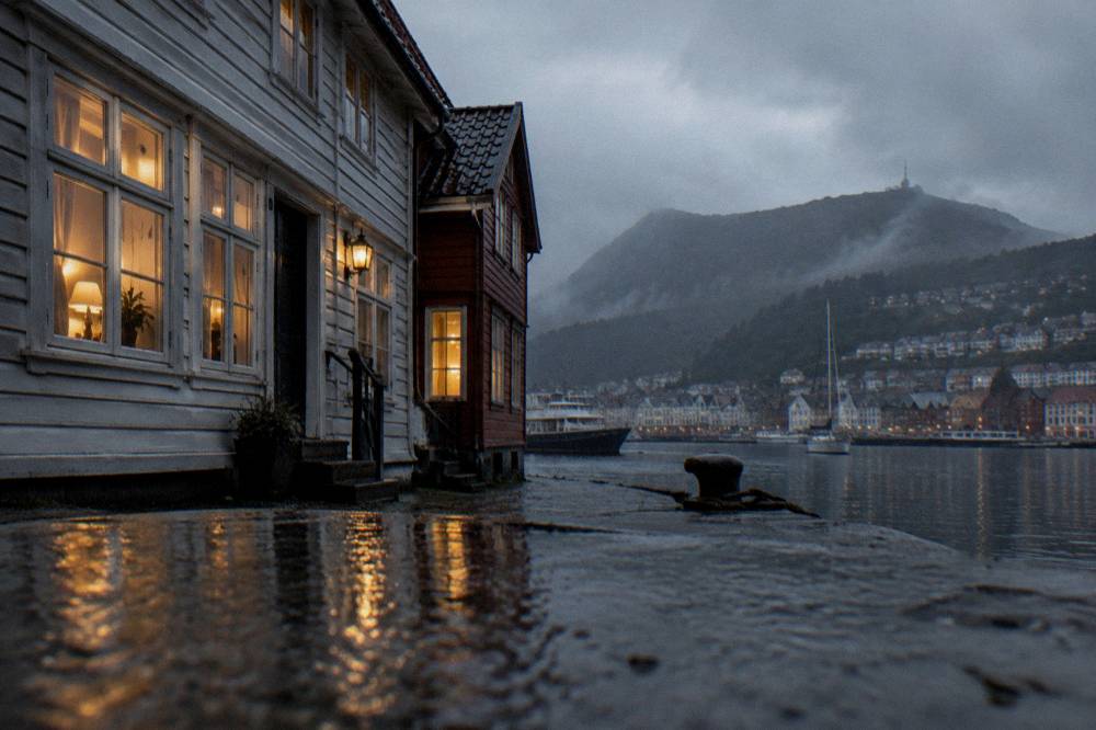 Warm yellow windows of a wooden Norwegian house on a dark rainy evening