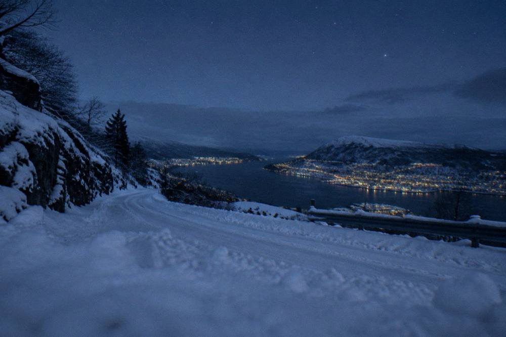 Deep snow covering a mountain road under a clear starry night sky
