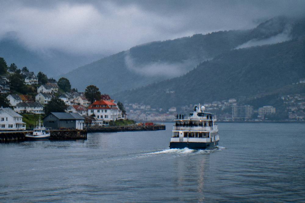 Blue evening light over a fjord cruise boat returning to a small Norwegian harbour
