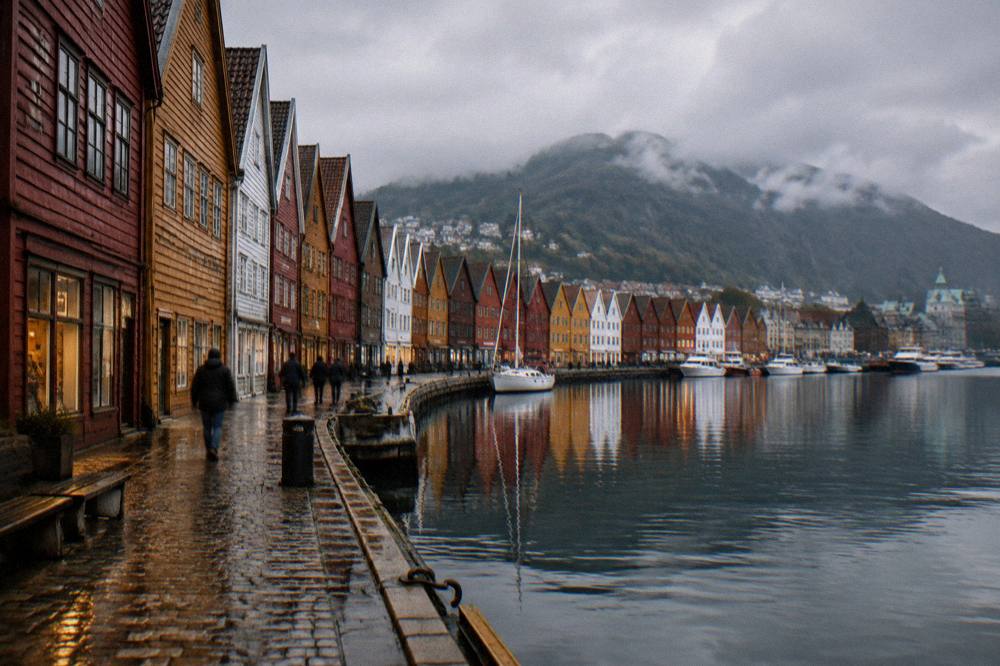 Colourful wooden warehouses along the Bryggen wharf in Bergen reflected in calm harbour water