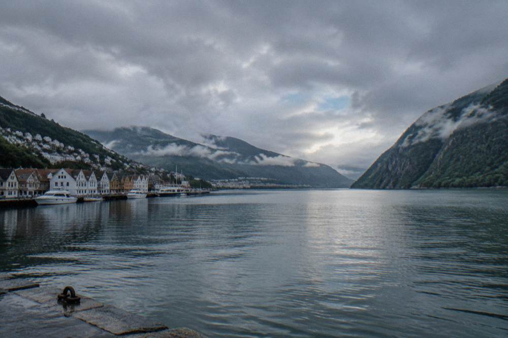 Rain clouds parting over a Norwegian fjord with steep forested cliffs on both sides