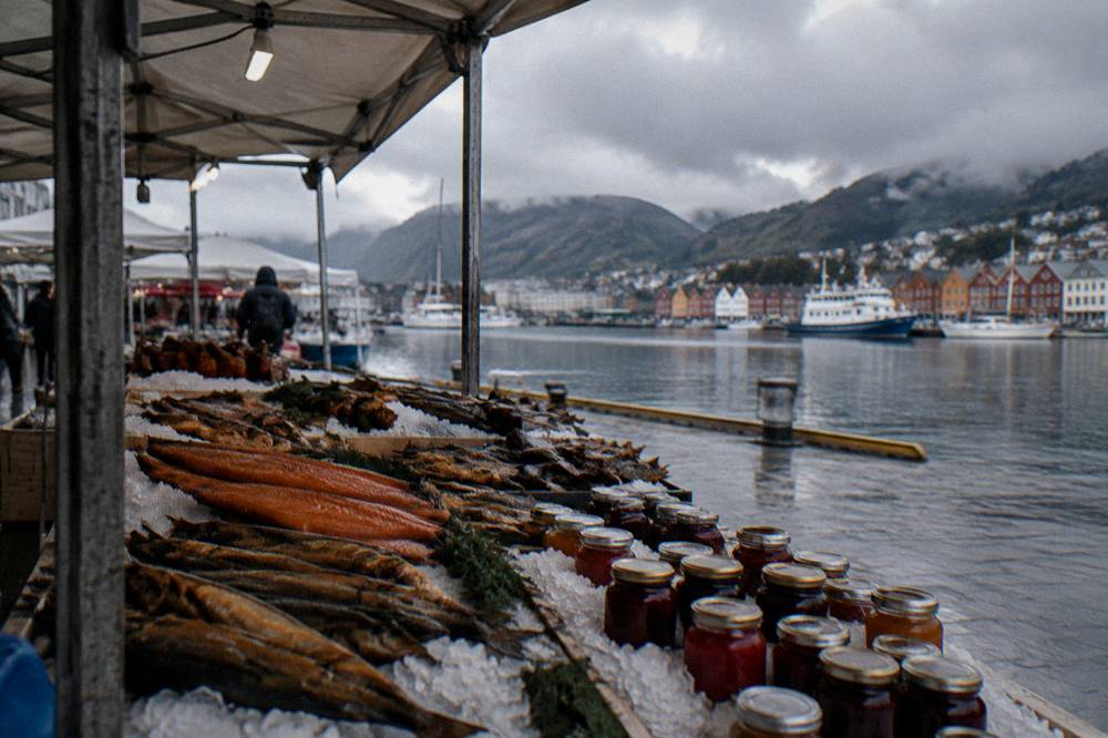 A market stall with smoked fish and jars of jam displayed on crushed ice