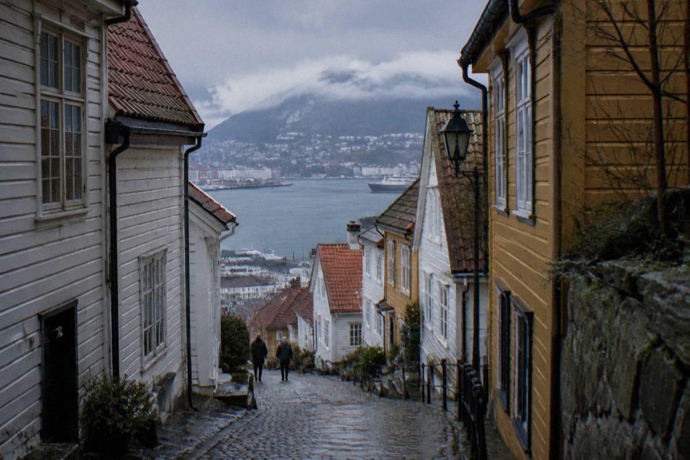 Narrow street of old wooden houses painted white and ochre on a hillside in Bergen