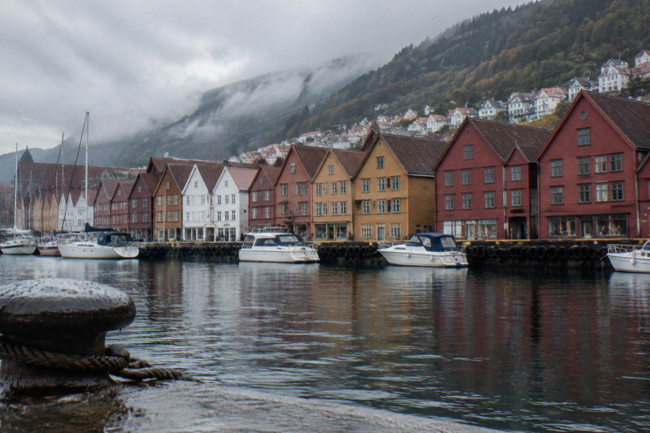 Colorful wooden Hanseatic buildings along the Bergen harbour front with small boats moored in the foreground