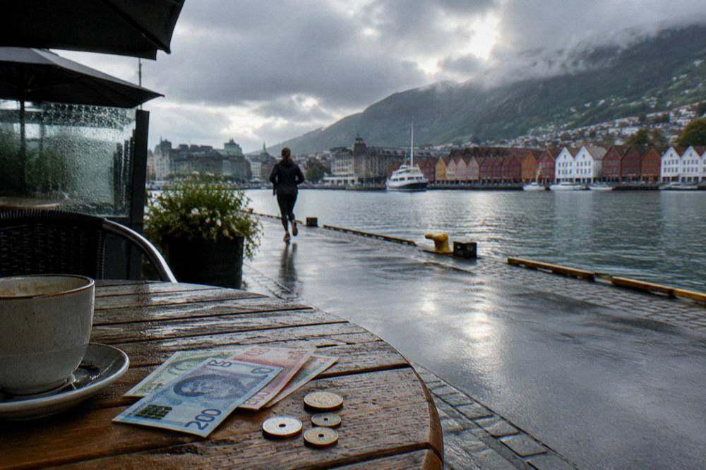 Norwegian banknotes and coins on a wooden cafe table beside a receipt and a cup of coffee