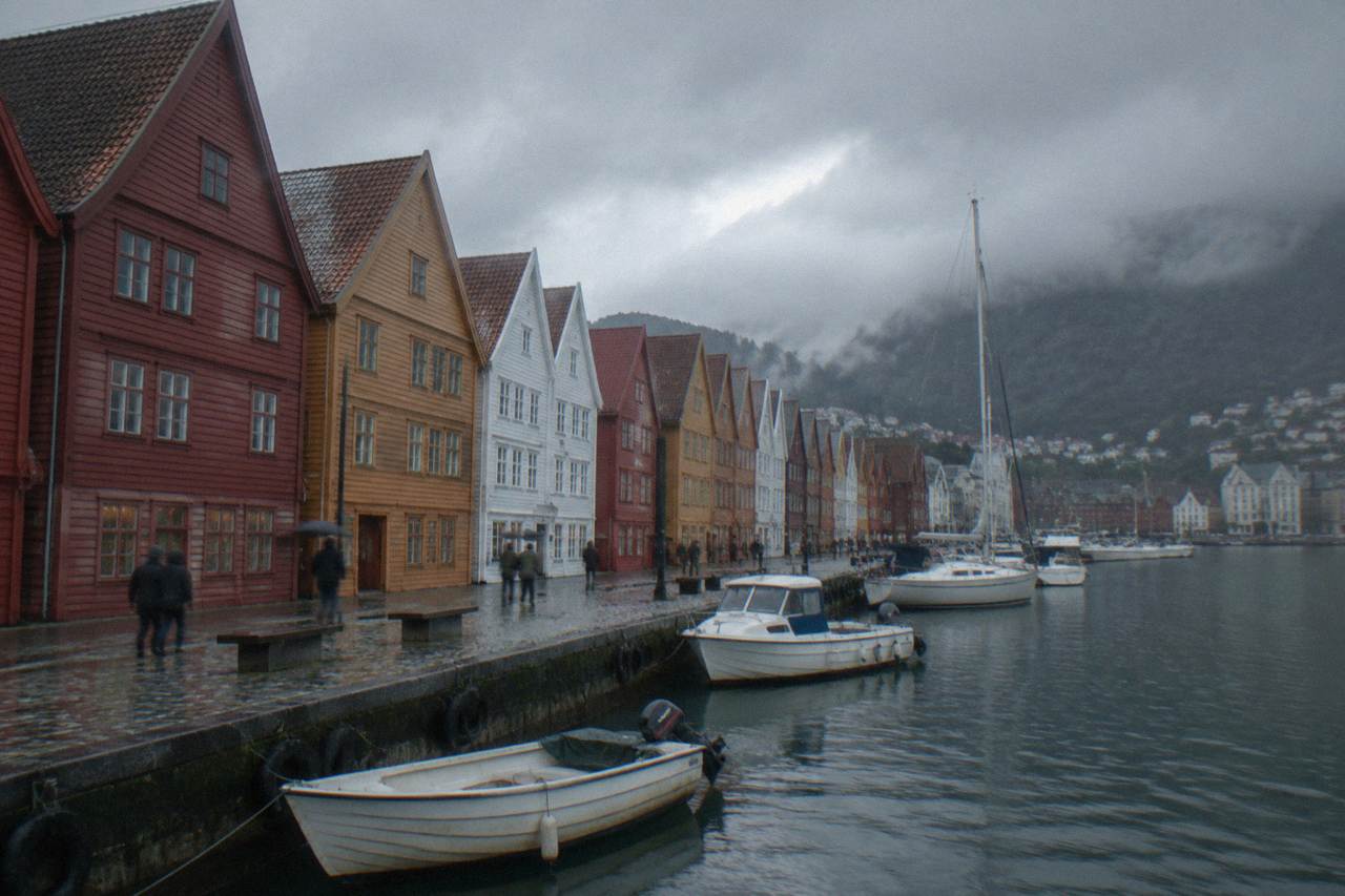 Colorful wooden Hanseatic buildings along the Bryggen wharf in Bergen with small boats in the foreground