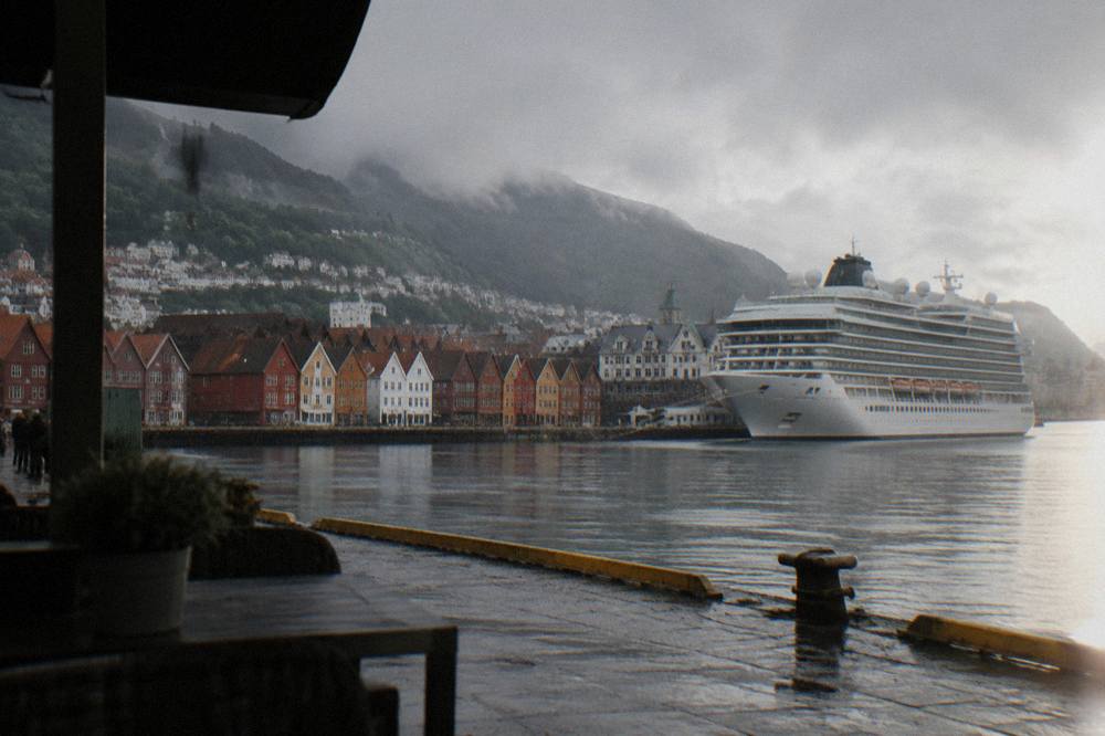 Cruise ship moored at a Bergen quay with the city's colorful waterfront houses behind it