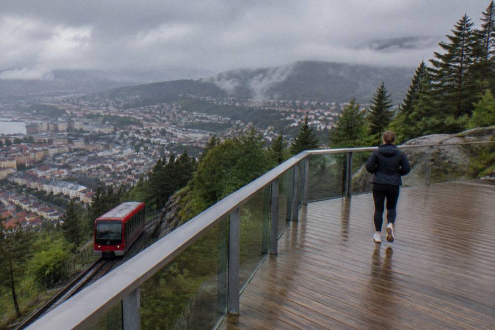 Red funicular cars on the Fløibanen track climbing the wooded slope above Bergen's rooftops