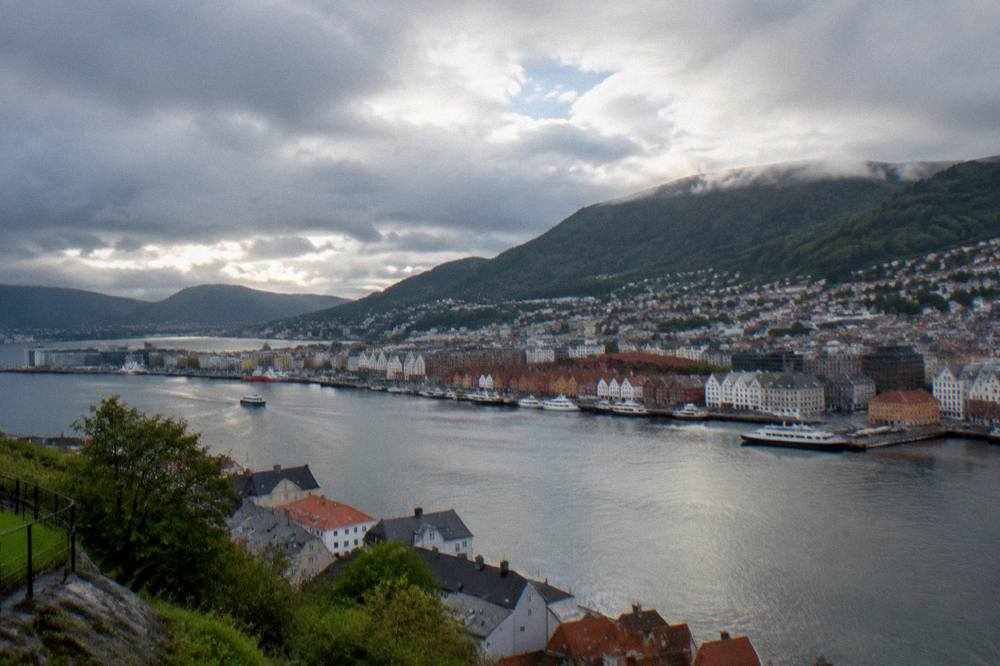Panorama of Bergen's harbour, wharf buildings and green mountainsides seen from above