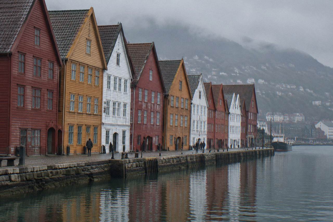 Colourful wooden houses of Bryggen wharf in Bergen reflected in the harbour on a bright day