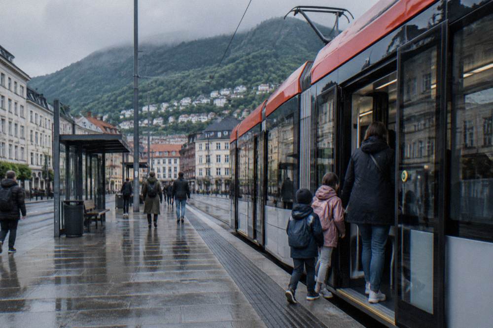 A family boarding a light rail tram at a Bergen city centre stop