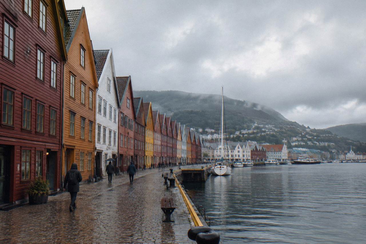 Colourful wooden Hanseatic warehouses along the Bryggen wharf in Bergen, with the harbour water in front and hills behind