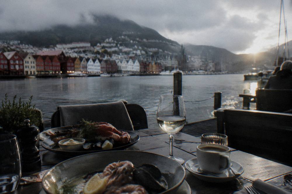A restaurant table in Bergen set with seafood dishes and coffee in evening light
